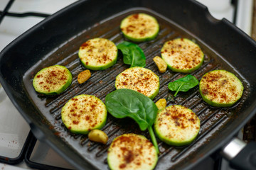 grilled zucchini with powdered paprika and spinach in a grill pan