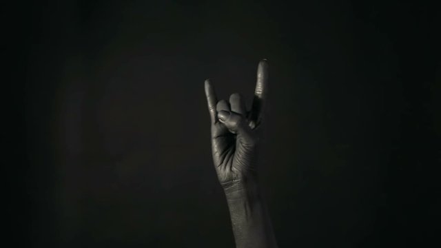 Goat gesture on a dark background. Black hand doing rock symbol. Hands up at a rock concert. Music star. Heavy metal concept. Black metal.