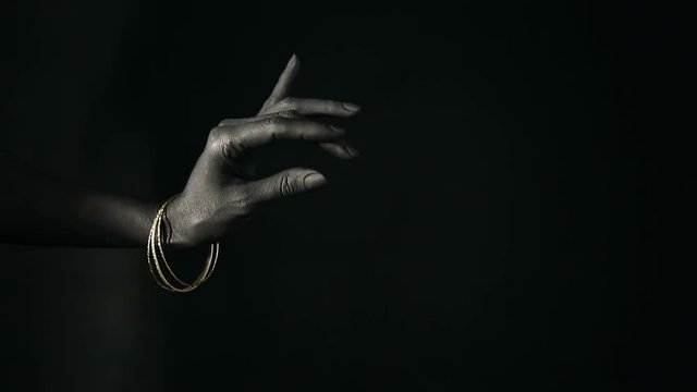Black woman's hand with Silver jewelry. Oriental Bracelets on a black painted hand. Silver Jewelry and luxury accessories on black background closeup. High Fashion art concept