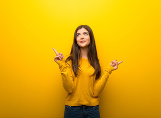 Teenager girl on vibrant yellow background pointing with the index finger a great idea