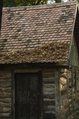 Old traditional wooden cottage with wooden door and red roof. Grandma's house from the woods. Fairy-tales hut.