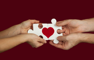 Puzzle with a red heart in the hands of a loving couple. Valentine's day concept.On a isolated background