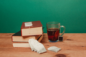 A cup of tea on the table near pile of books