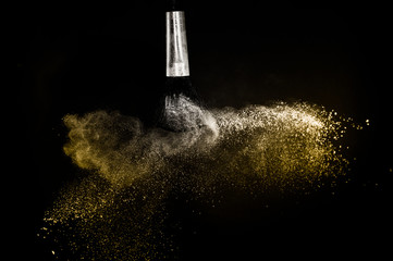 Cosmetic brush with golden cosmetic powder spreading for makeup artist in black background, look like a luxury mood.