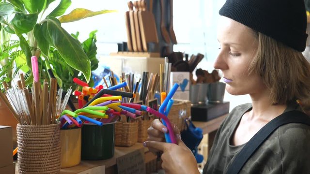 Female Choosing Eco-Friendly Straws At Eco Store. Sustainable Lifestyle Concept. Zero waste, Plastic Free Items. Stop Plastic Pollution.