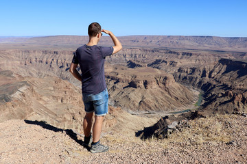 a man looks out over the Fish River Canyon - Namibia