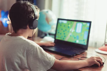 Little dependent gamer kid playing on laptop at home © sakkmesterke