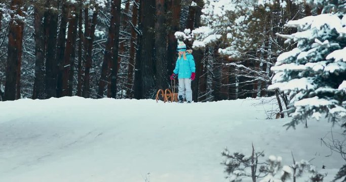 WIDE Cute little girl child preparing for a sledge ride down the hill. Child plays outdoors in snow, winter fun. 4K UHD 60 FPS SLOW MOTION
