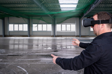 Construction worker standing at indoor construction site wearing vr eyeglasses or goggles, with space for your copytext or imagery projection