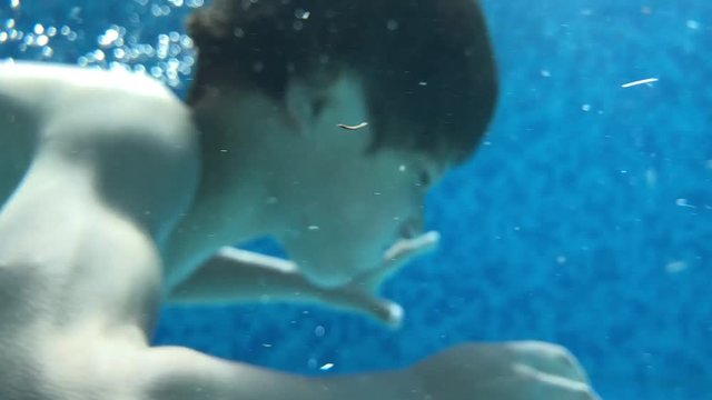 Child boy diving inside swimming pool during summer vacations