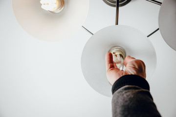 Unscrewing and replacing the bulb in the lamp. The man unscrews the burnt bulb, exchanges it for a...