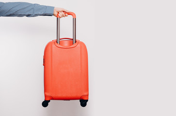 The man is giving by hand A red travel suitcase on wheels, isolated on a white background. Travel concept, packing up before departure. Preparing for travel, going on vacation, break, rest.