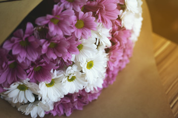 Close up of fresh bouquet bunch of white and violet chrysanthemums in craft paper lying on the table. Commercial photo for advertising flower shop