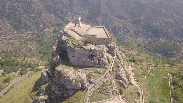 Stunning orbit 4k aerial of rock with Catholic cross in Bova, Calabria, Italy