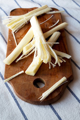 String cheese on rustic wooden board, side view. Healthy snack. Close up.