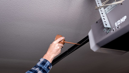 Handyman applies oil to a garage door opener chain