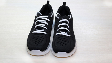 Black sport unisex sneakers with white sole and white laces on white background