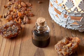 A bottle of myrrh essential oil with myrrh resin on a table
