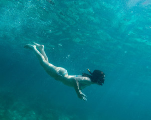 Woman swimming underwater on a blue sea and clear water with good visibility for snorkeling.