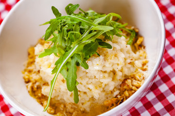 Risotto with gorgonzola, walnuts and arugula on white plate. Close up