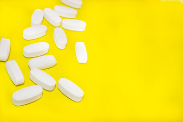 white medical pills, on yellow background, closeup