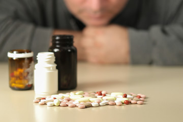 Depressed man beside a lot of pills, suicide concept