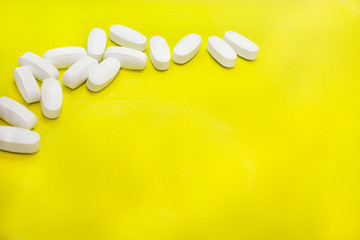 white medical pills, on yellow background, closeup