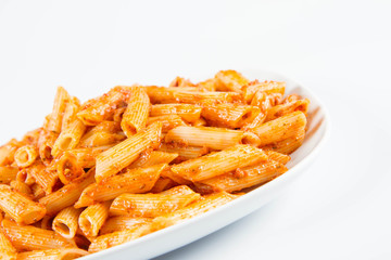 Penne with pesto on a plate on a white background