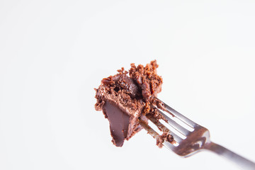 Chocolate cake eaten with a fork on a white background