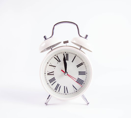 White retro alarm clock on a white background at around twelve o'clock