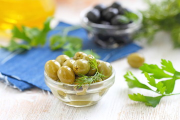 Green and black olives in glass bowls and olive oil