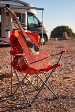 Vertical view guitar on chair near camper vehicle