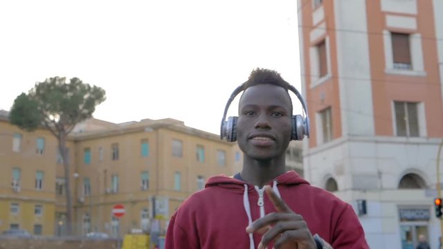 Black african young man listening music and dancing in the street-slow motion