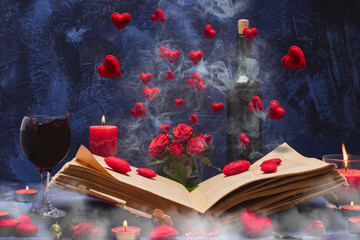 Valentine day. Book in the smoke with flying hearts. Book, hearts, candles, fog, smoke, flowers, wine on a blue background. Magic for lovers. Splash of red wine. A wonderful romantic evening . Love.