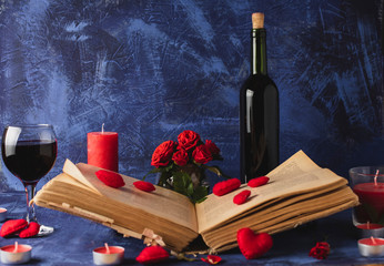 Valentine day. Book in the smoke with flying hearts. Book, hearts, candles, fog, smoke, flowers, wine on a blue background. Magic for lovers. Splash of red wine. A wonderful romantic evening . Love.