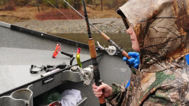 Young boy going fishing on a boat in the rain.