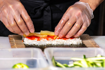 closeup of chef hands rolling up sushi on the kitchen