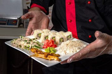 closeup of chef hands rolling up sushi setting on plate on kitchen