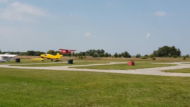 red plane with a propeller sits down and takes off at the airport