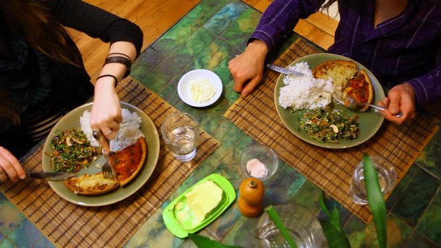 Couple having a meal together, sitting at a table and eating a quiche with salad and rice for diner - fixed angle, seen from above