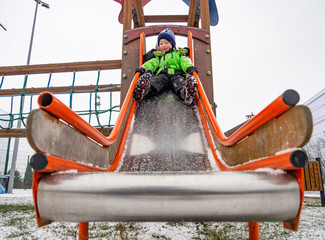 Smiling two boys sliding down playground slide