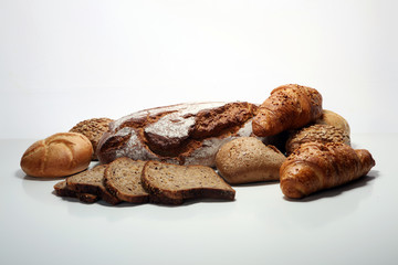 Different kinds of bread and bread rolls on board from above.