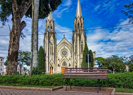 Bench of the square with the church cathedral of Botucatu under blue sky with clouds at dawn in the background