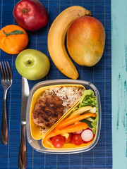 Lunch box with appetizing food and on light wooden table.