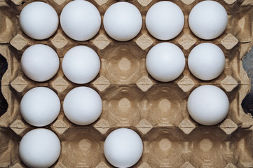 White chicken eggs in a cardboard box with empty space, background