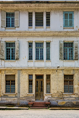 Facade of old building with wooden door and wooden windows with glass