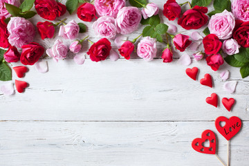 Roses and red hearts on a wooden background