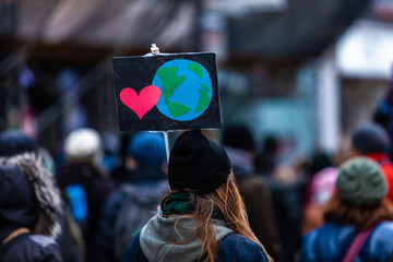 Activists marching for the environment. French sign seen in an ecological protest with a planet earth and a heart. Shot from behind