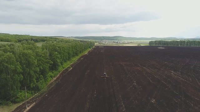 Aerial view of old blue tractor plowing field