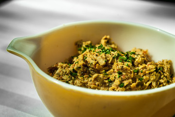 Big yellow bowl of tofu salad and greens. Close up shot taken outside on a white tablecloth.